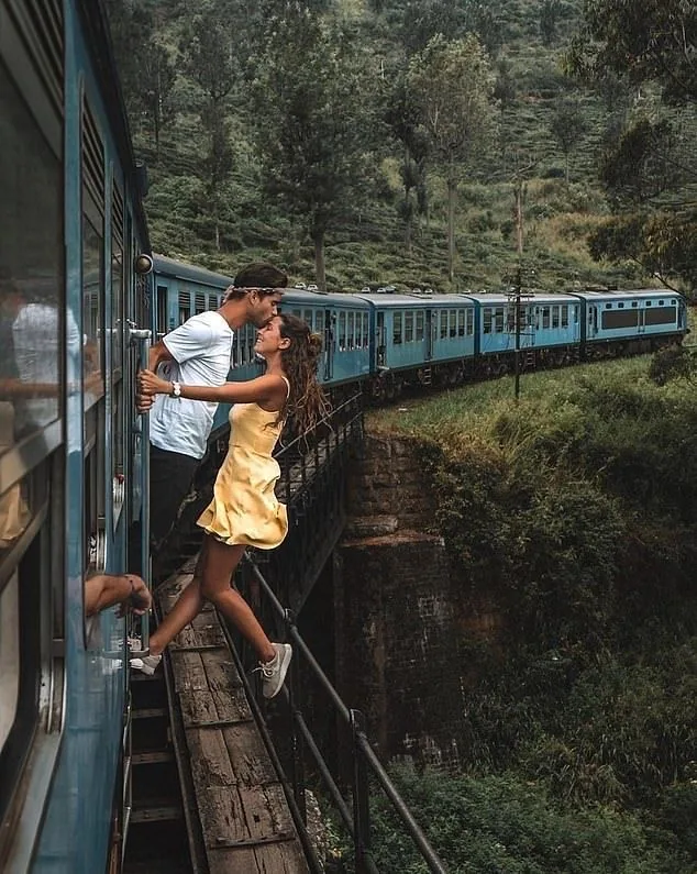 Two travelers enjoy the open doorway of a train crossing the hill country.