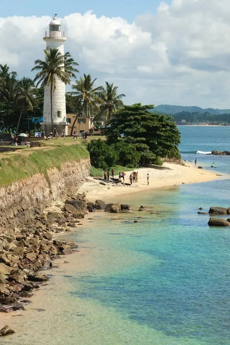 Galle Lighthouse stands above the sea and beach beside the historic fort.