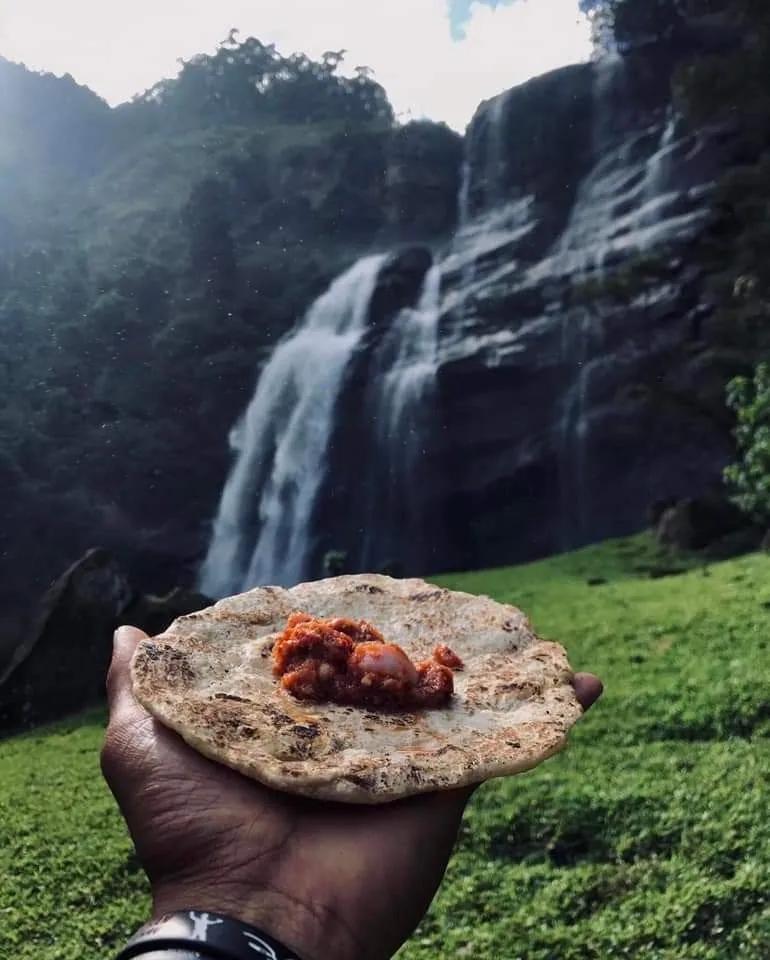 A hand-held local flatbread is enjoyed beside a waterfall in the green highlands.