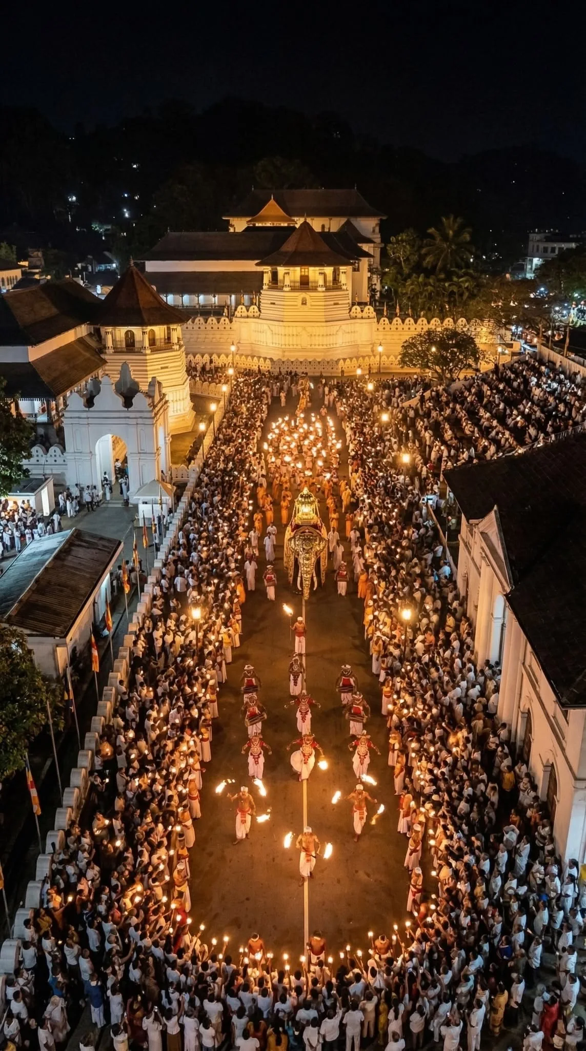 The Temple of the Tooth and its courtyard glow during a night-time procession in Kandy.