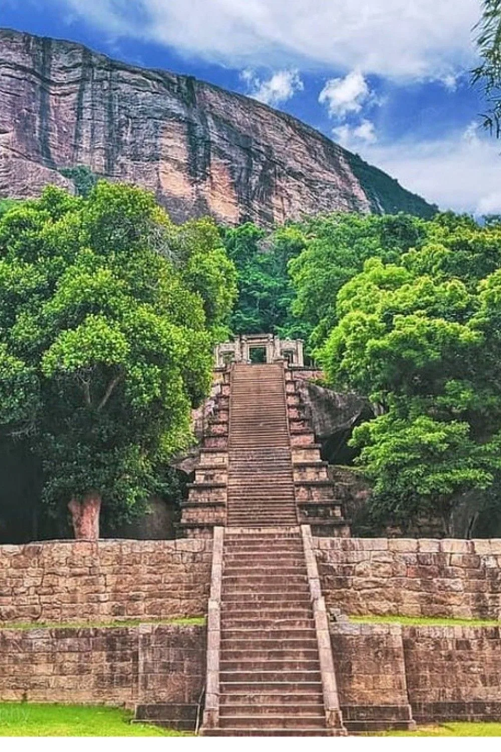 Stone steps climb toward an ancient gateway at the base of Sigiriya Rock.