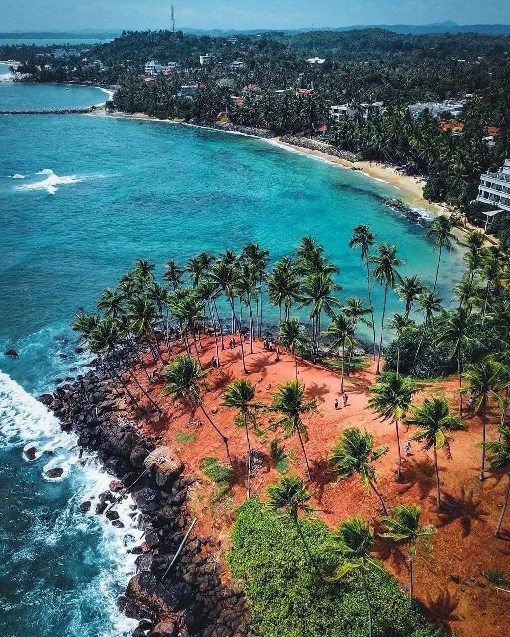 Aerial view across a palm-lined bay and rocky coast in southern Sri Lanka.